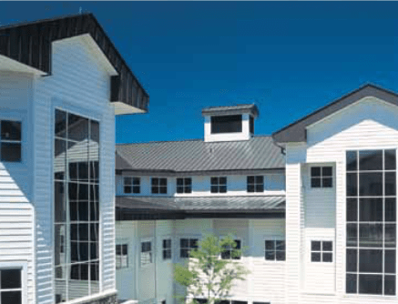 White multi-building structure with large windows, black trim, and a dark roof against a clear blue sky.
