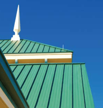 Green metal roof with white trim and a spire against a clear blue sky.