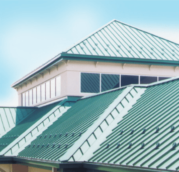 Green metal roof on a building with blue sky backdrop.