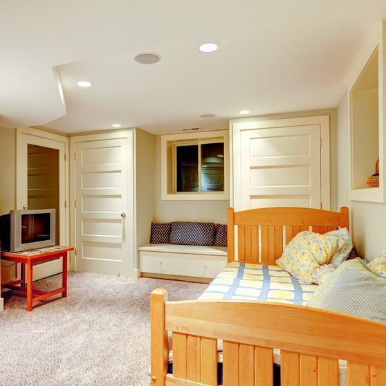 Bedroom with wooden beds, built-in cabinets, and a window seat. Tan walls, carpet.