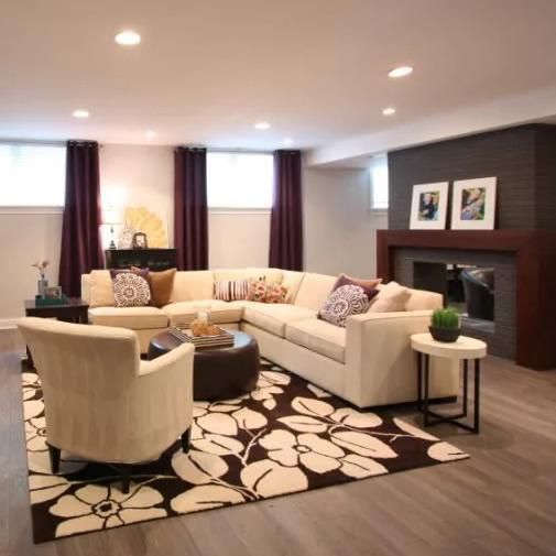 Cozy living room with sectional sofa, floral rug, fireplace, and dark purple curtains.
