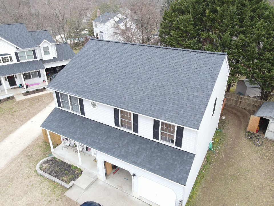 Two-story white house with dark gray roof, black shutters, and attached garage.