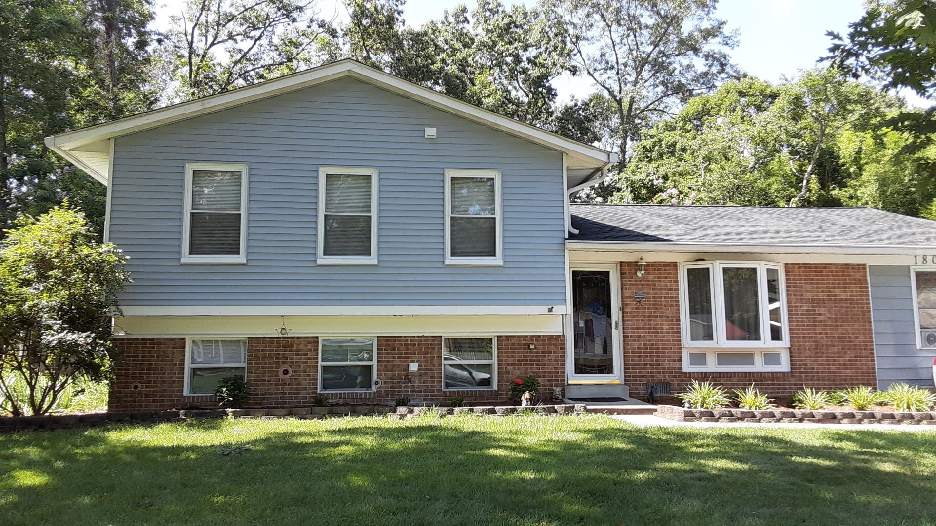 Two-story house with blue siding, brick base, and green lawn.