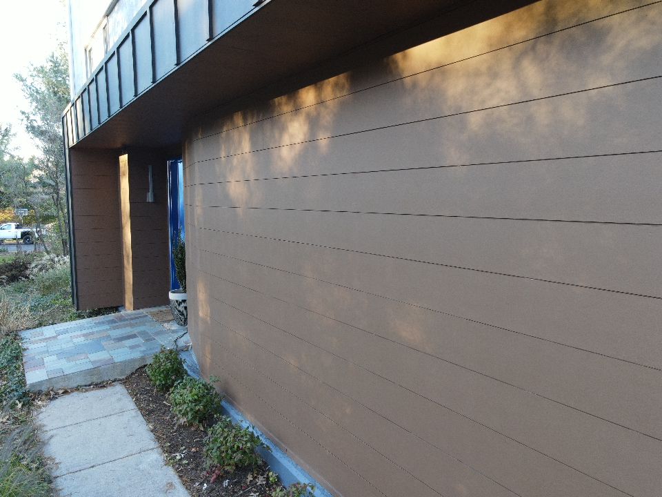 Brown house exterior with horizontal siding and a blue door.
