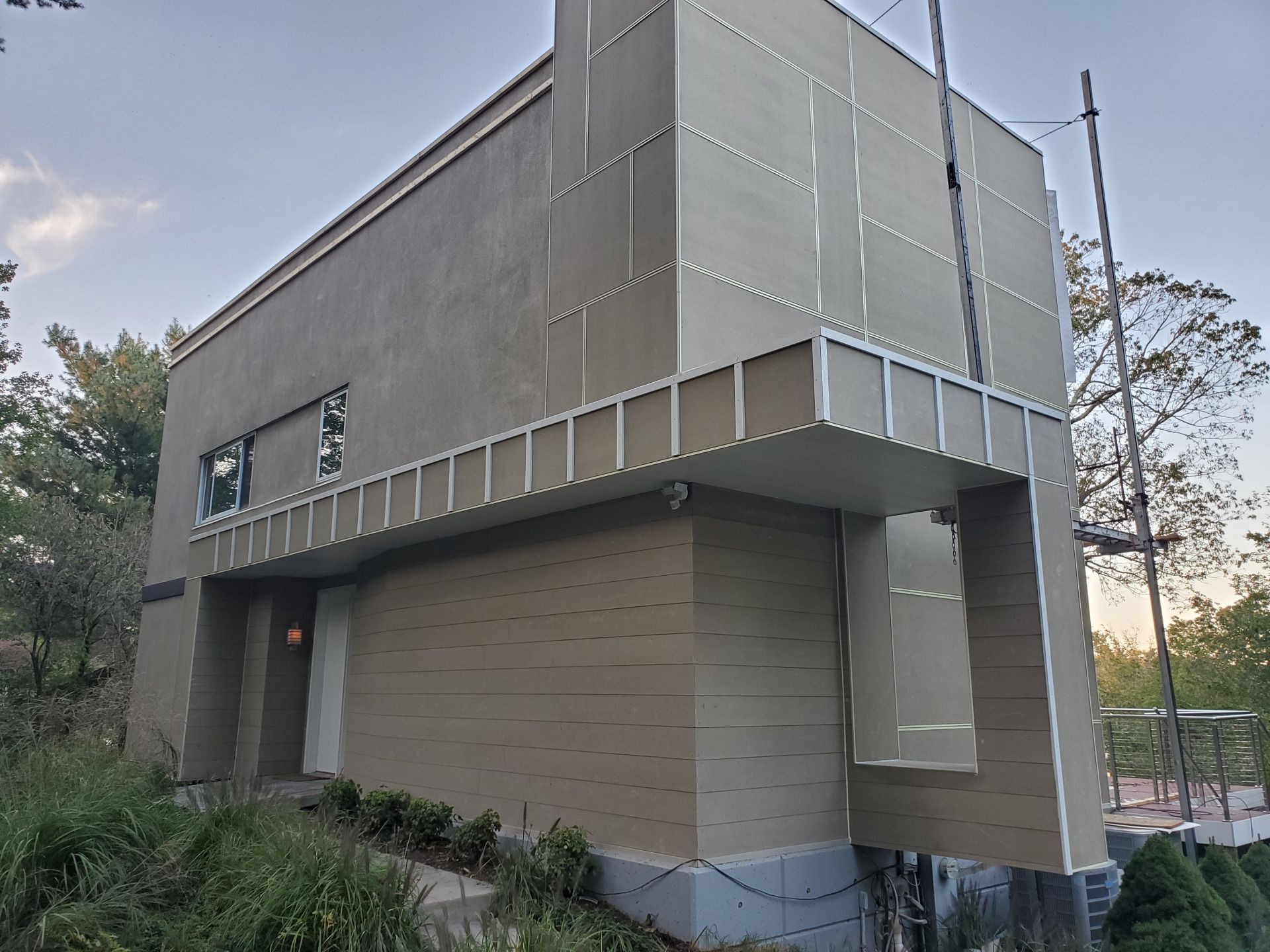 Beige modernist building with metal trim, set on a hillside.