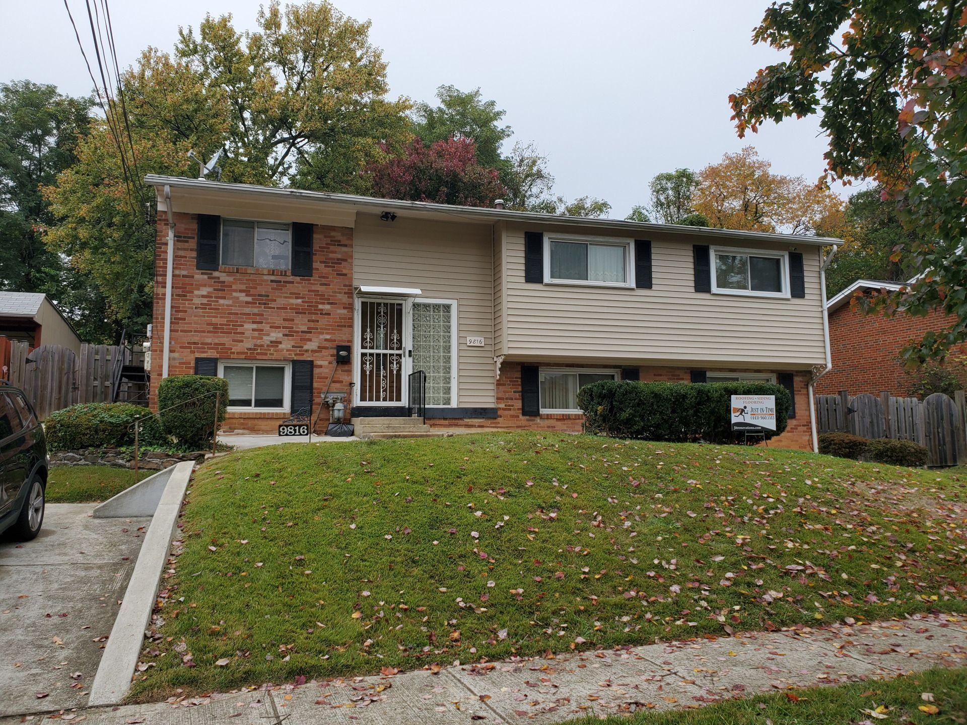 Two-story suburban house with brick and beige siding, a small front yard, and autumn trees.