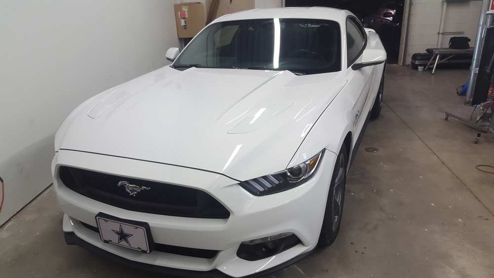 A white Ford Mustang parked inside a garage.