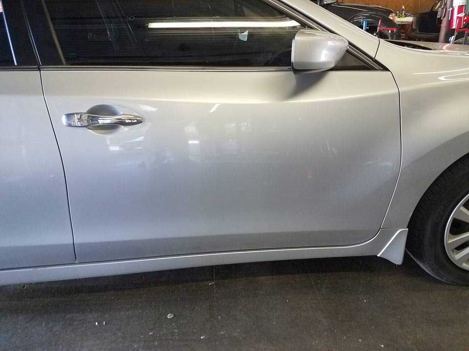 Side view of a silver sedan focusing on the passenger side door and front wheel.
