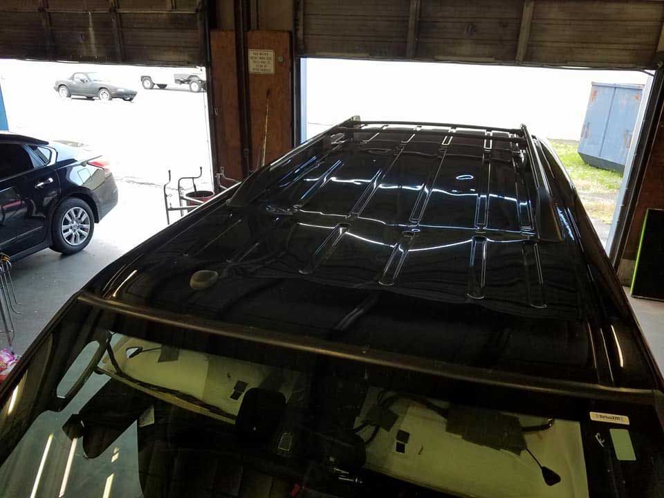 High-angle view of an automobile’s exposed metal roof structure inside a repair shop.