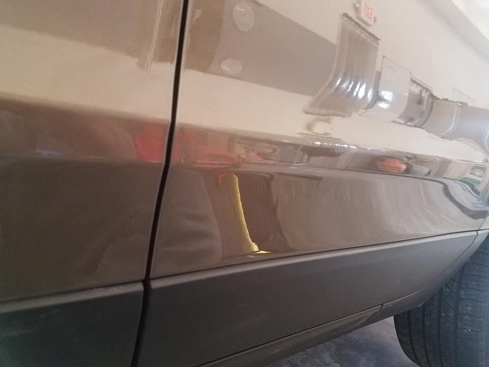 A close-up view showing the panel gap between two bronze-colored car doors, with a black trim piece along the bottom.