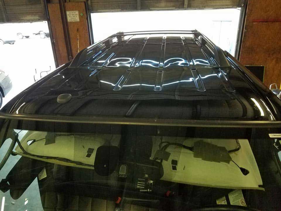 A high-angle view inside a vehicle, showing the dark metal roof structure and wiring exposed behind the windshield.