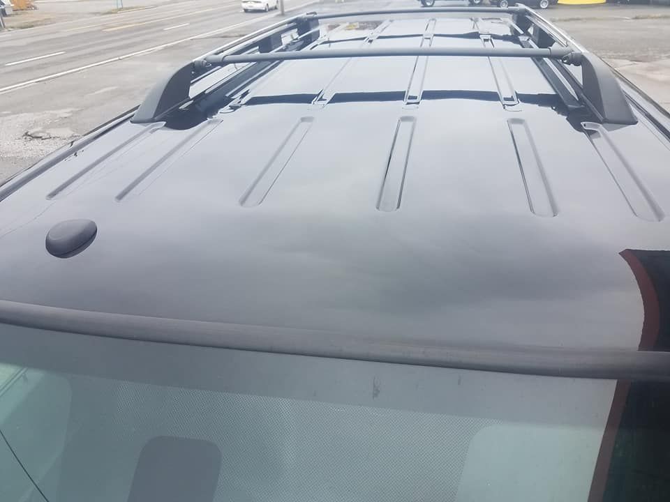 A close-up, high-angle view of a black car roof featuring a black roof rack rail system.