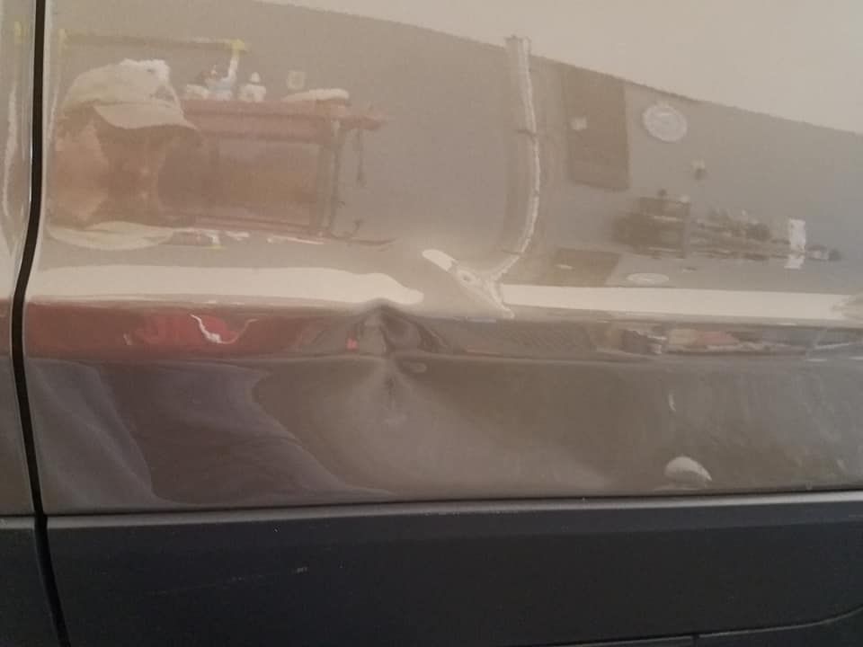 A dent on a tan car door panel, positioned just above the black plastic trim.