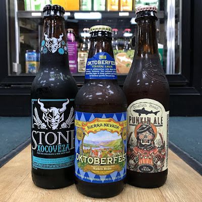 Four craft beer bottles on a counter, including Stone Xocoveza and Punkin Ale, with an Oktoberfest bottle in back