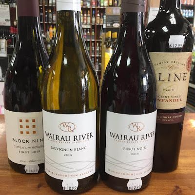 Four wine bottles displayed on a shelf, including Wairau River Sauvignon Blanc and Pinot Noir.