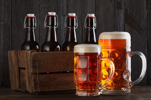 Beer bottles and frothy beer mugs on a dark wooden table