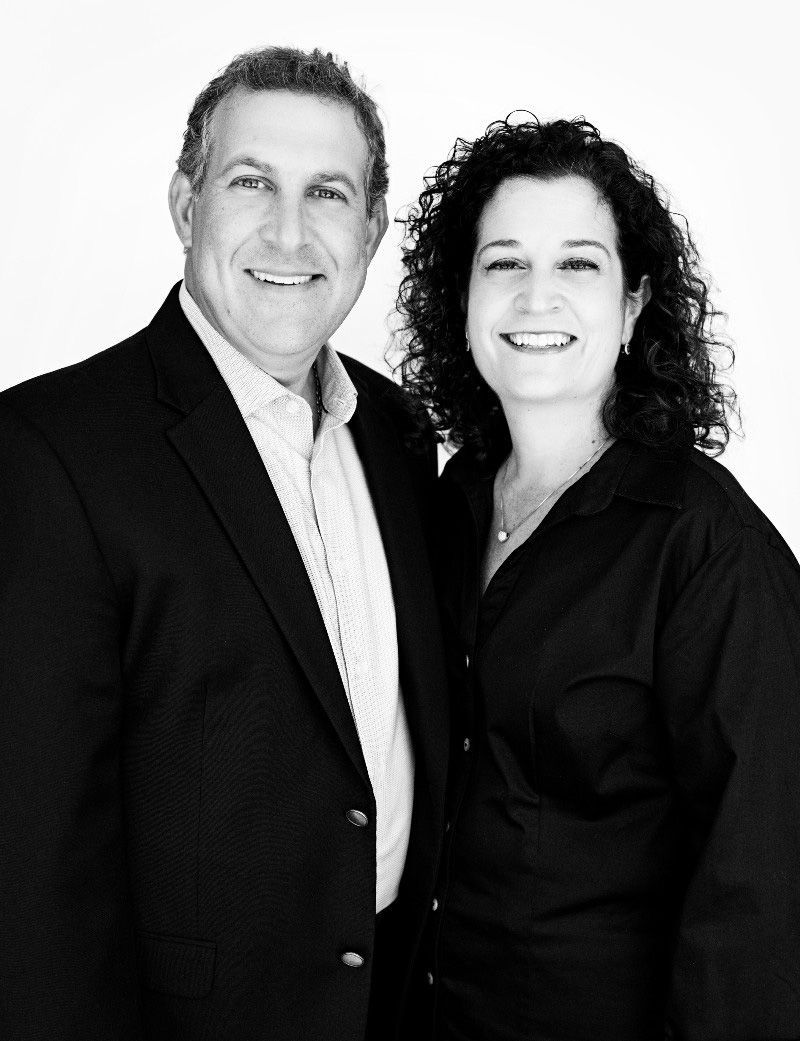 Man and woman smiling, posed closely together, against a white background.