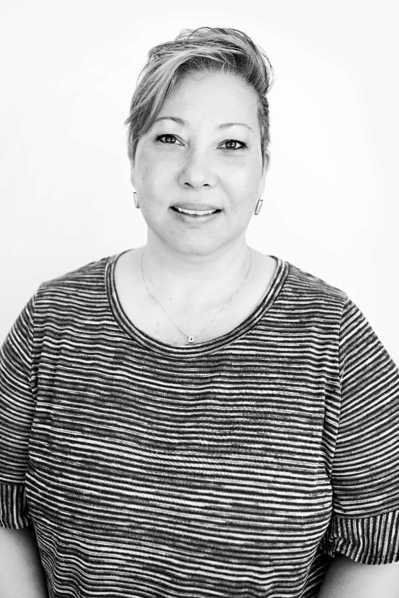 Woman with short, light hair wearing a striped shirt smiles against a white background.