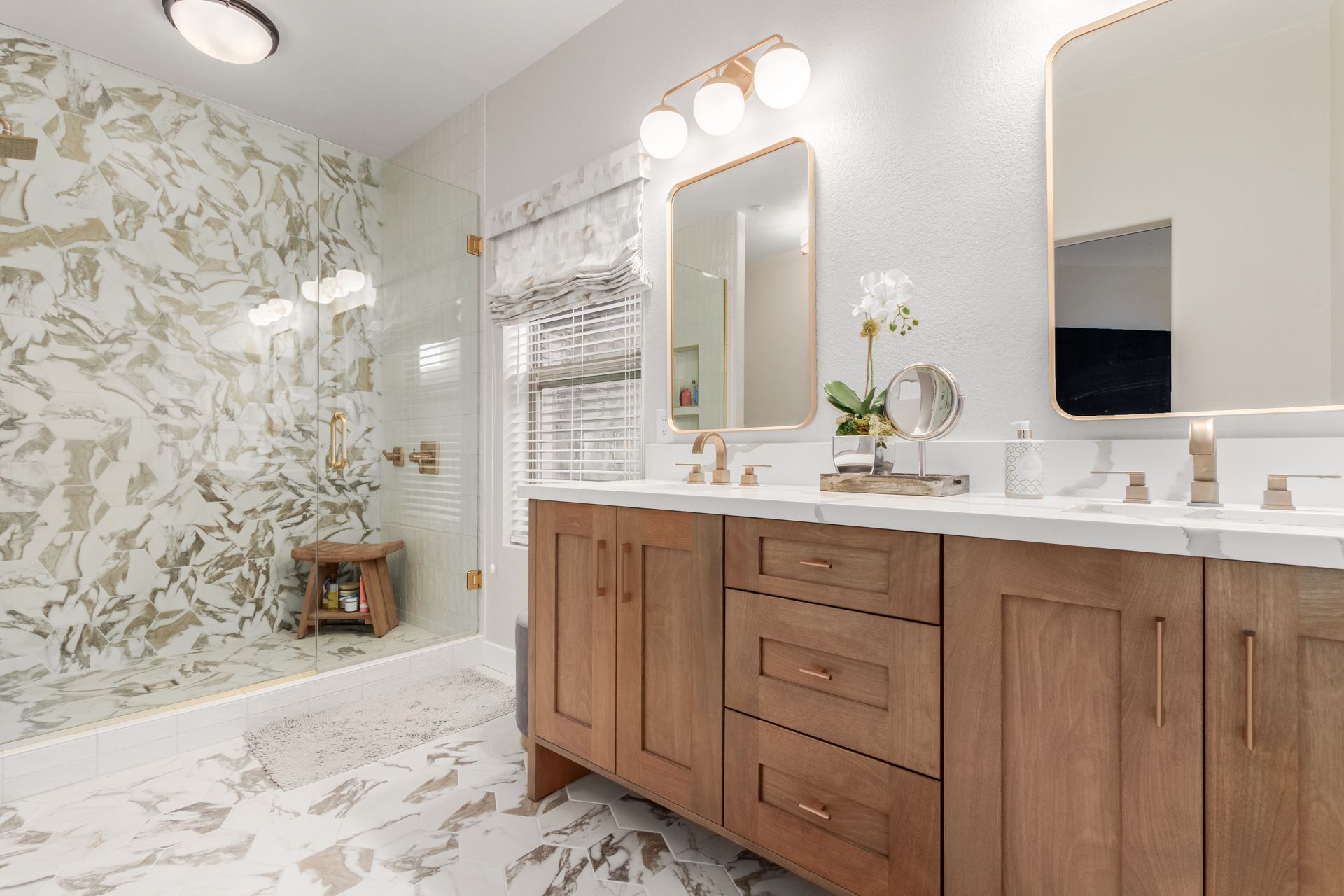 A bathroom with two sinks , a mirror and a walk in shower.