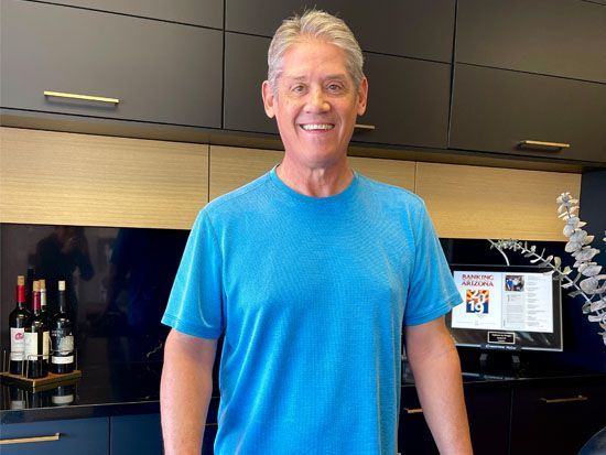 A man in a blue shirt is standing in a kitchen.
