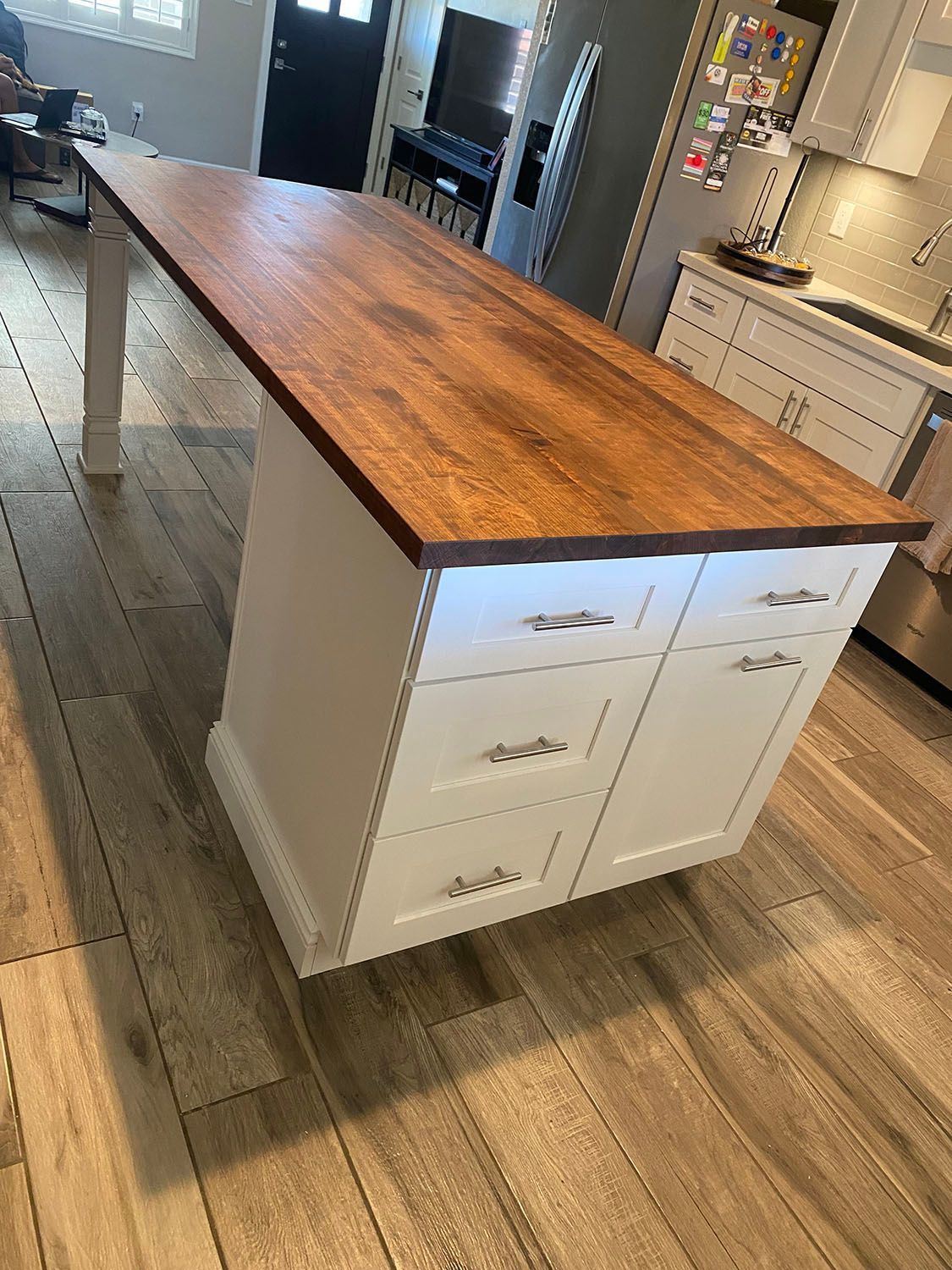 A kitchen island with a wooden top and white cabinets.