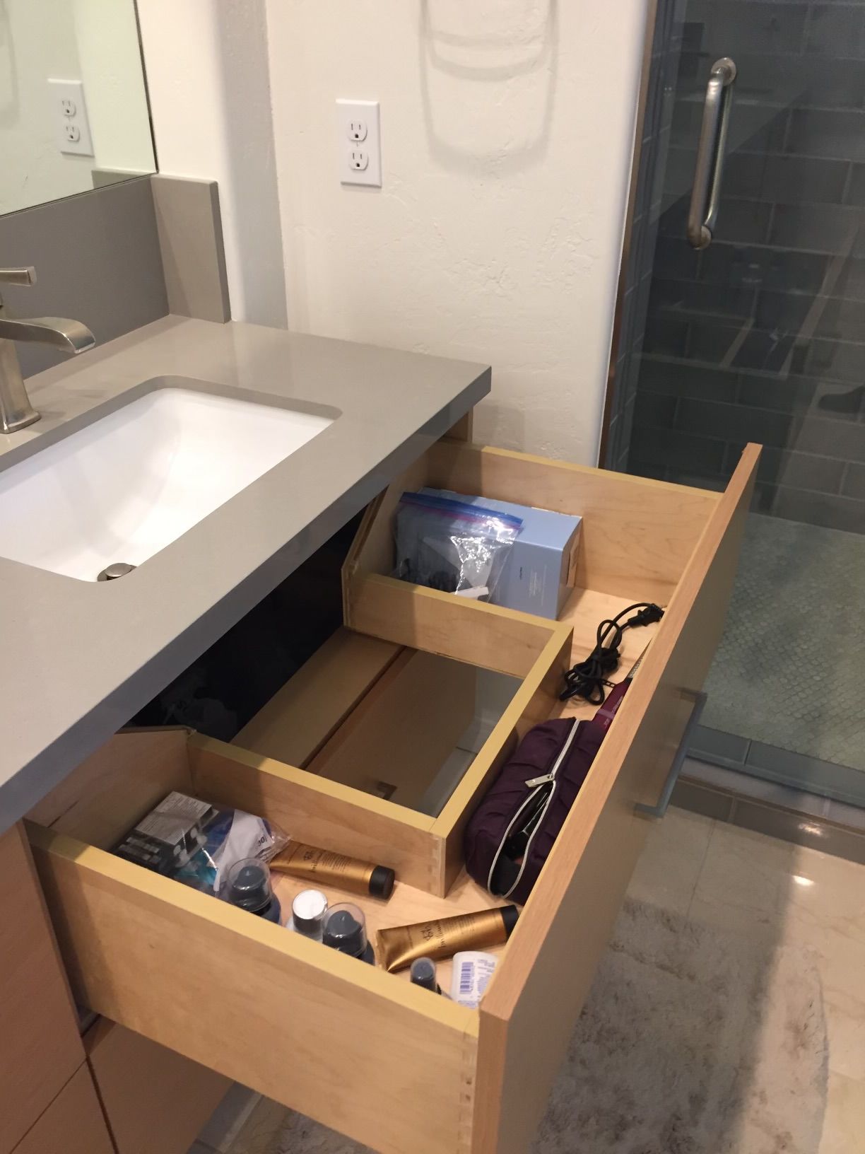 A bathroom with a sink and a drawer filled with various items
