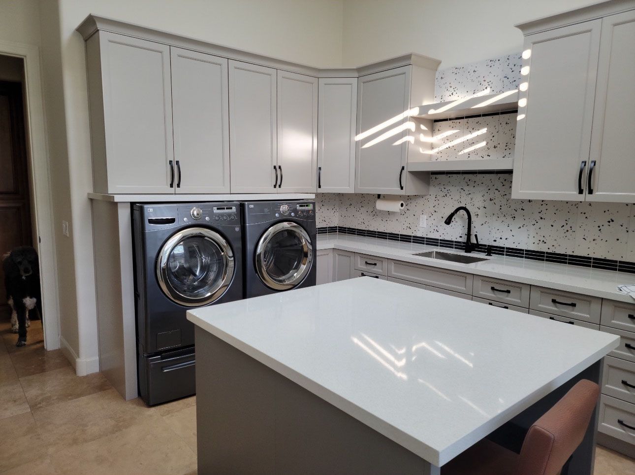 A kitchen with a washer and dryer and a large island.