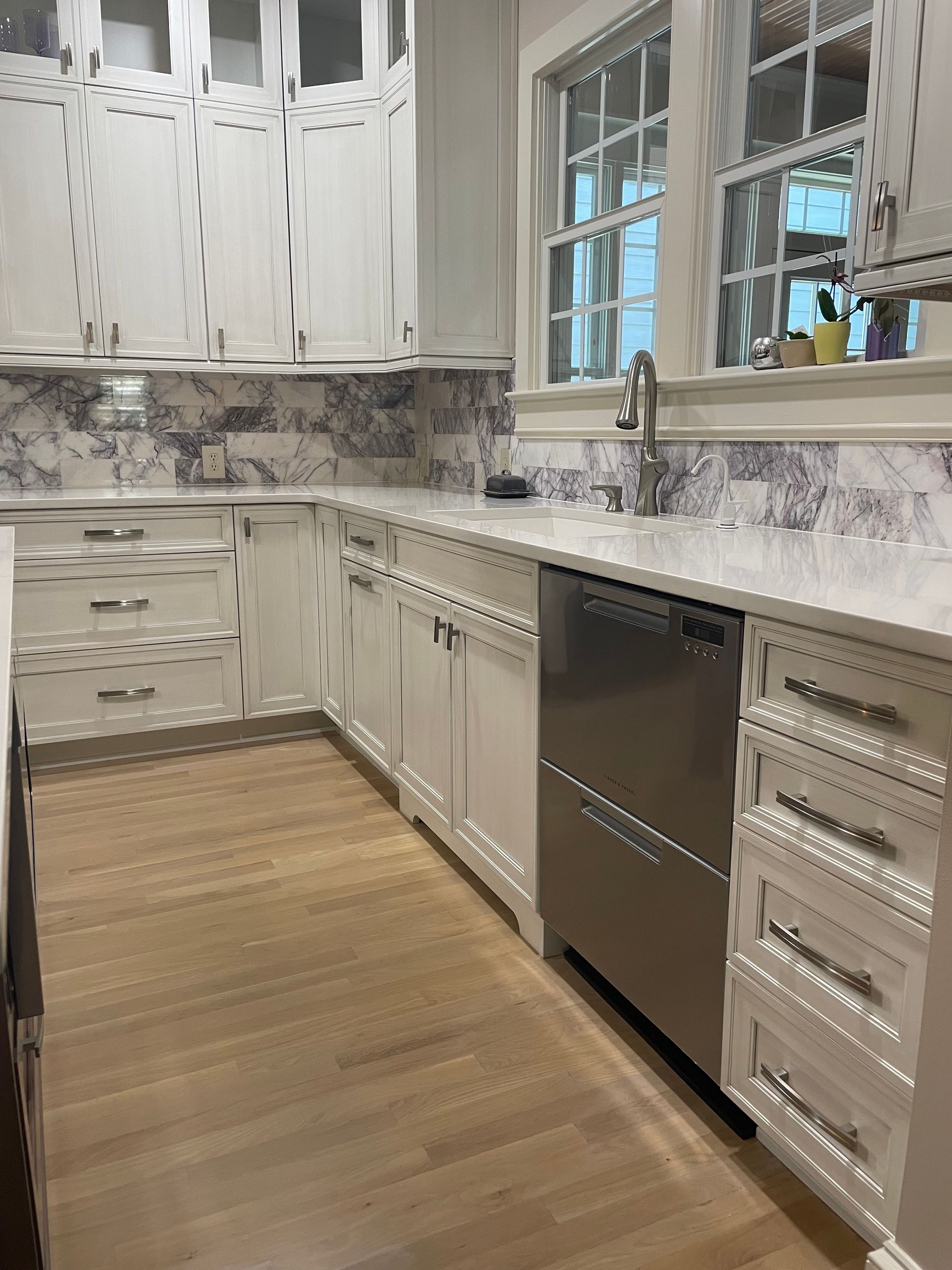 A kitchen with white cabinets and a stainless steel dishwasher.
