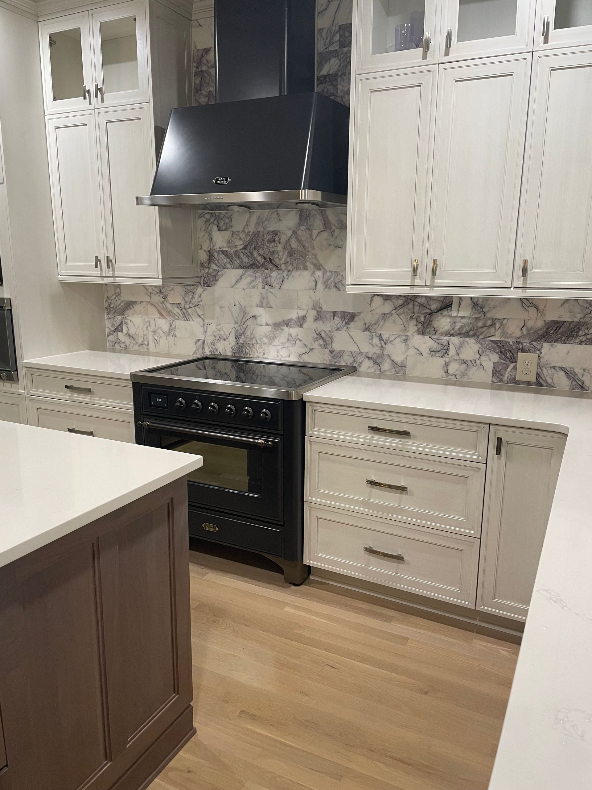 A kitchen with white cabinets and a black stove top oven.