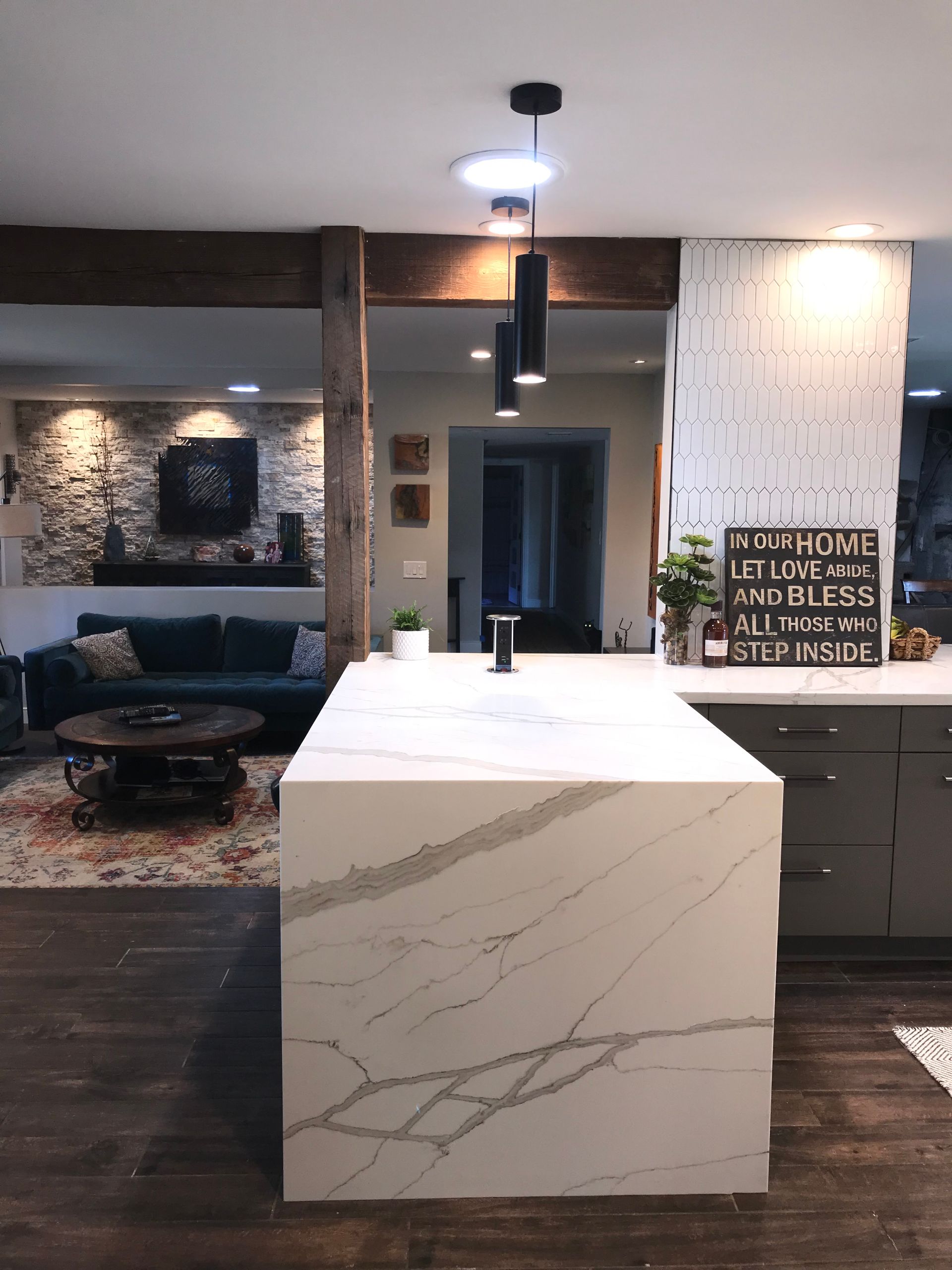 A kitchen with a large island and a living room in the background.