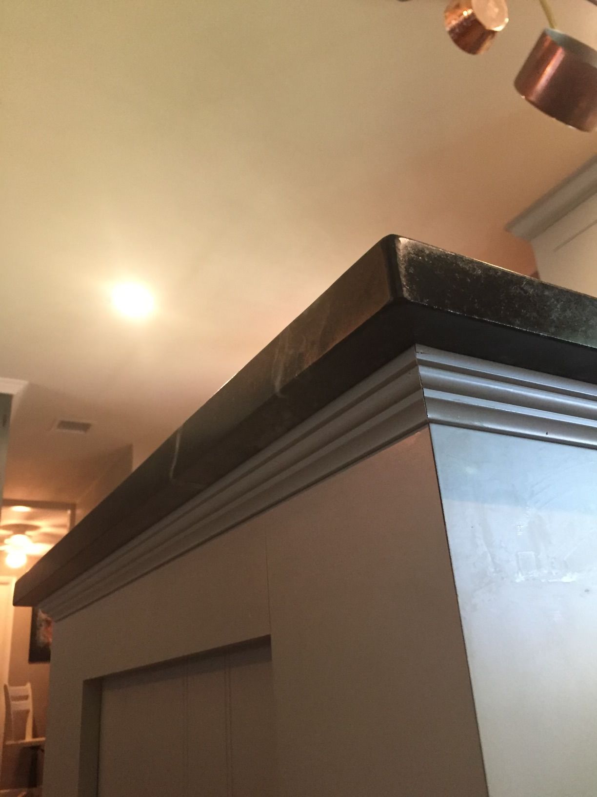 A gray cabinet with a black counter top in a kitchen