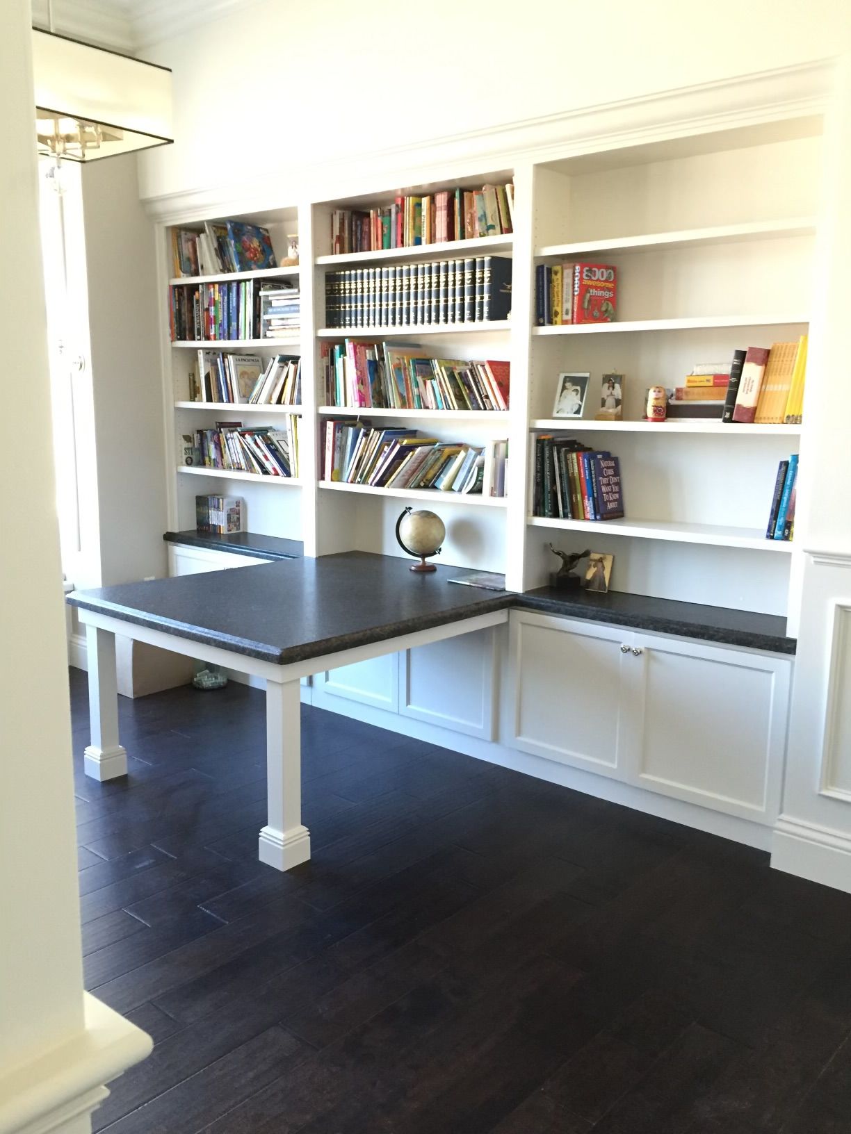 A room with a table and shelves filled with books.