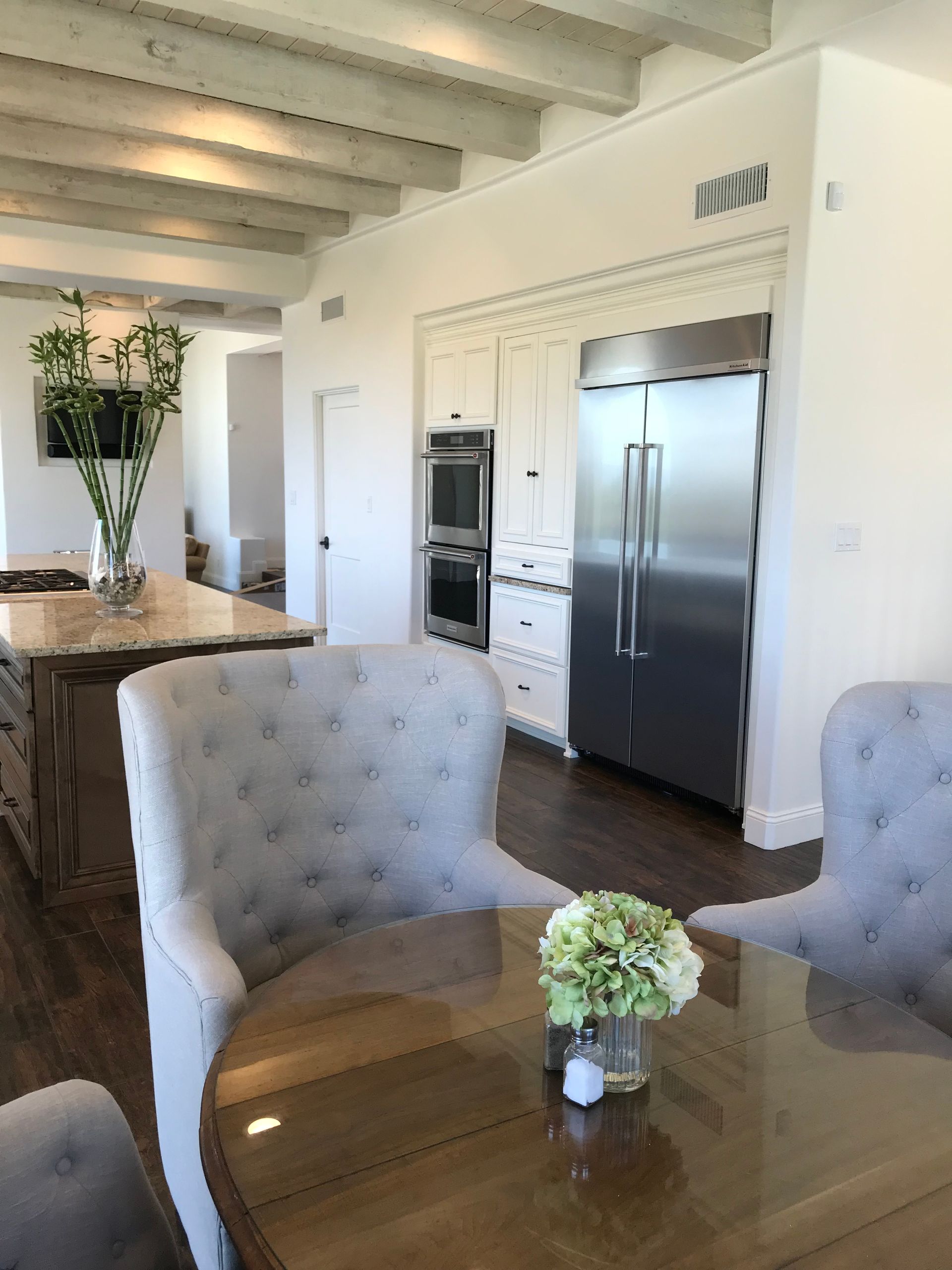 A kitchen with a table and chairs and a stainless steel refrigerator