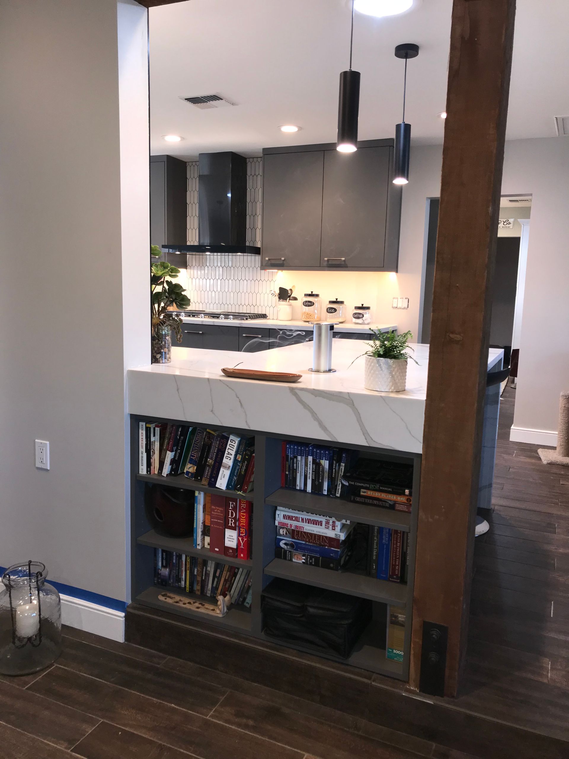 A kitchen with a marble counter top and bookshelves