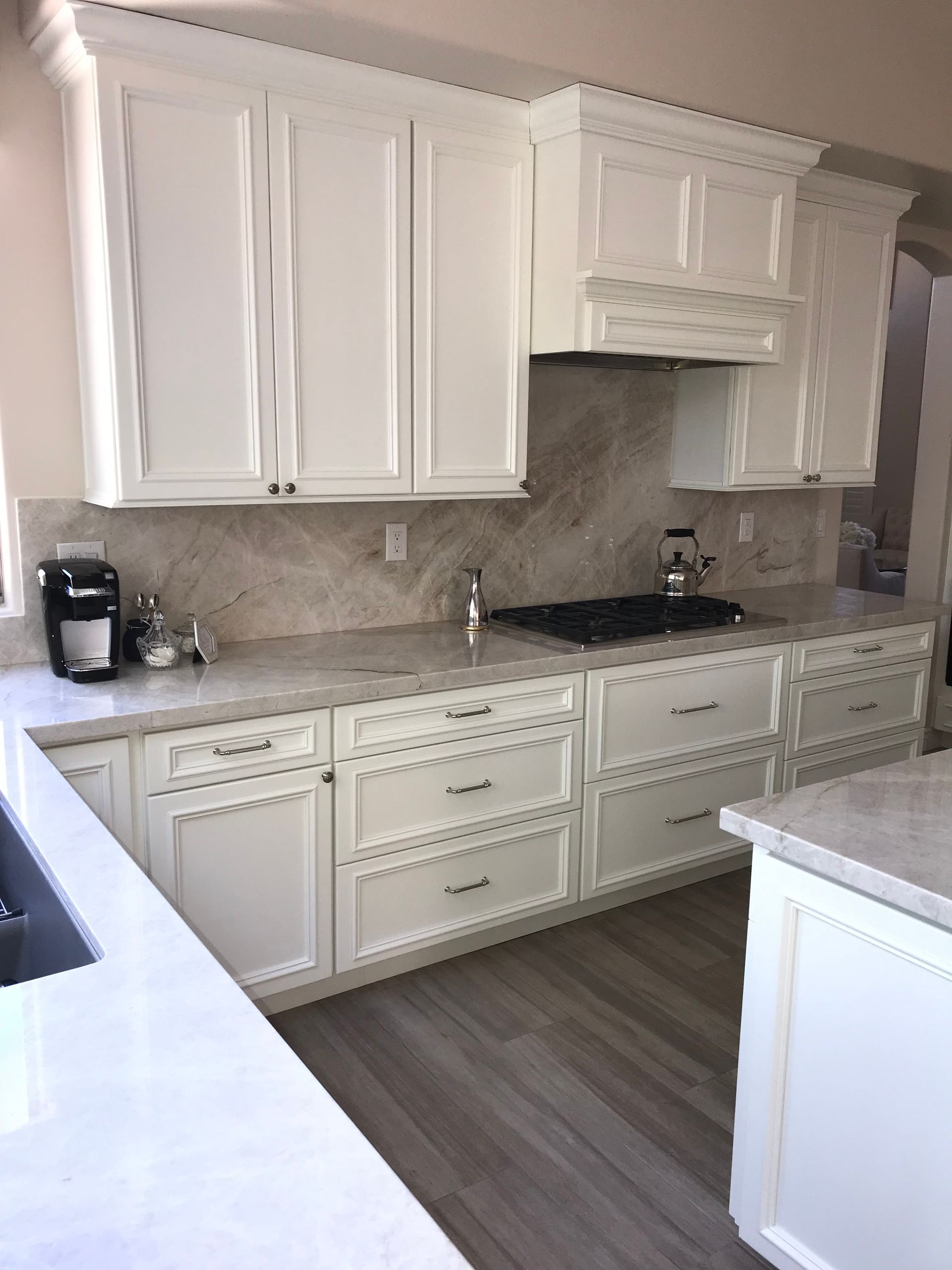 A kitchen with white cabinets and granite counter tops.