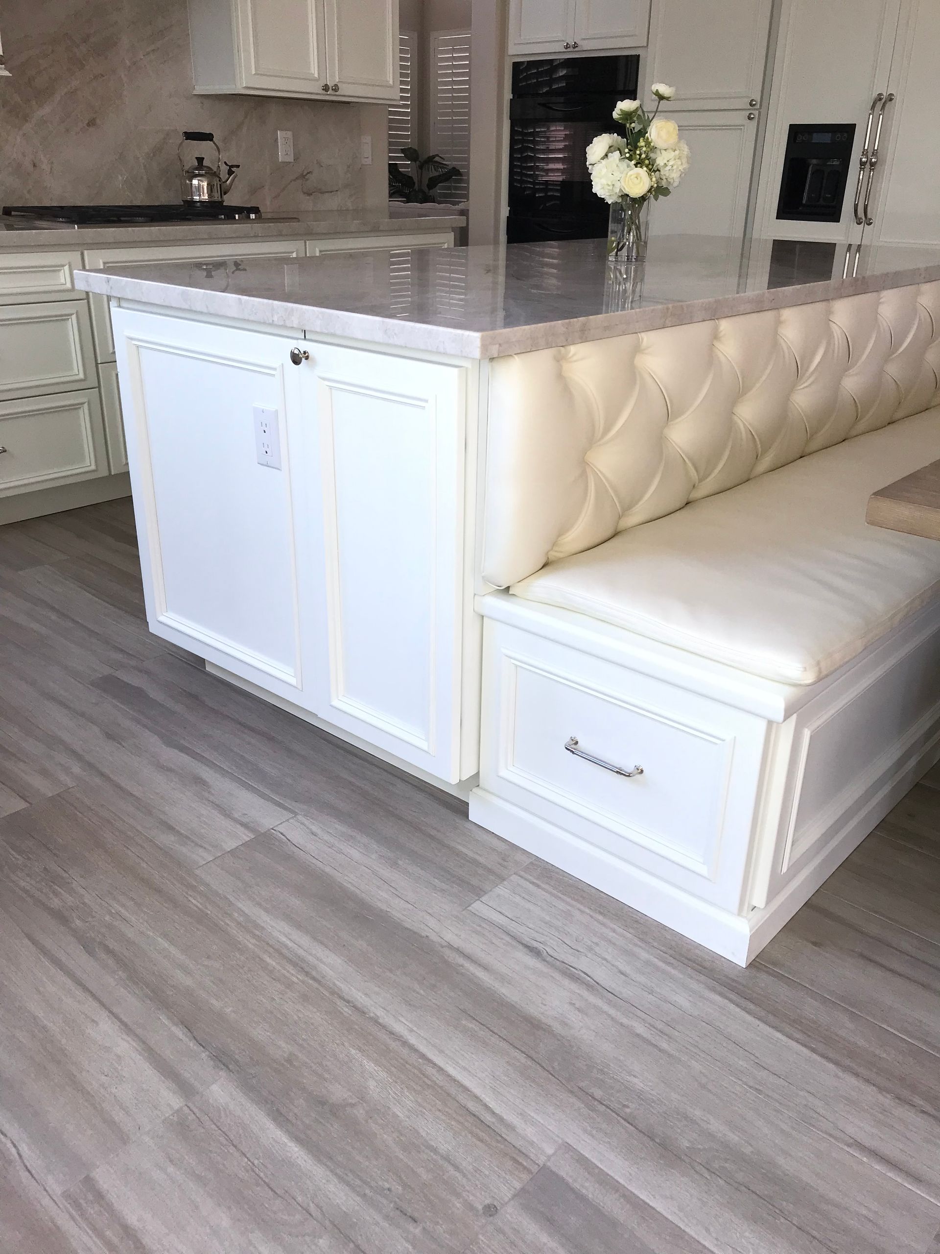 A kitchen with white cabinets and a white bench