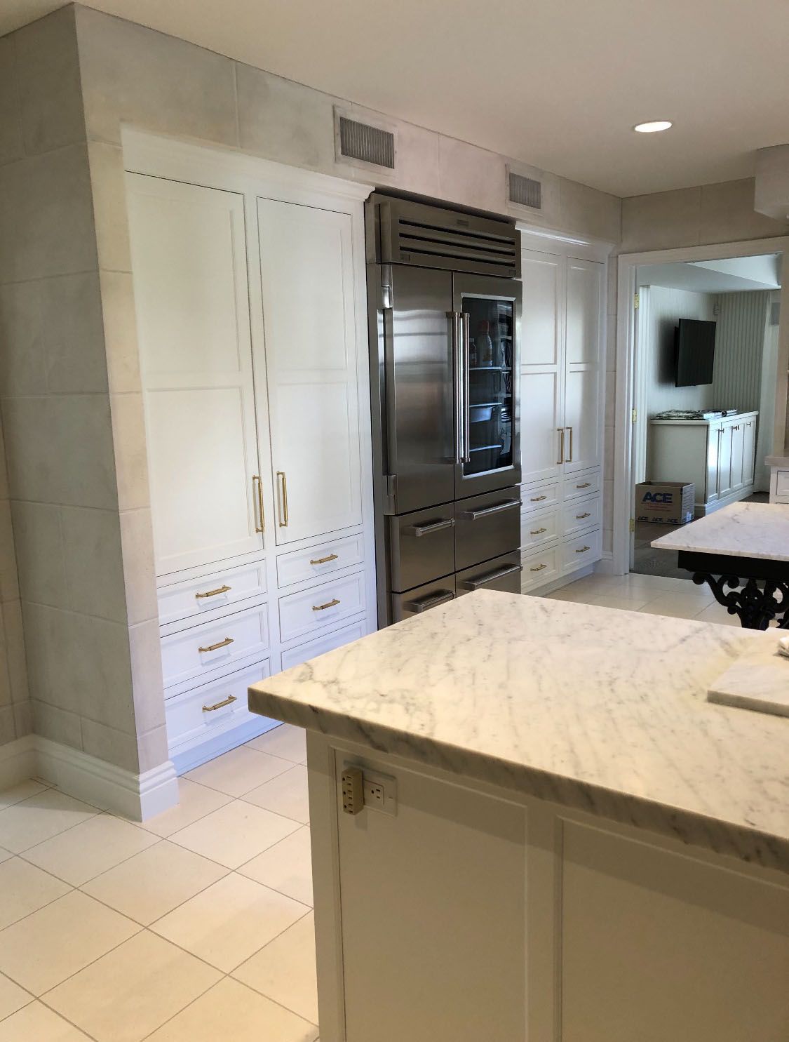 A kitchen with white cabinets and a stainless steel refrigerator.