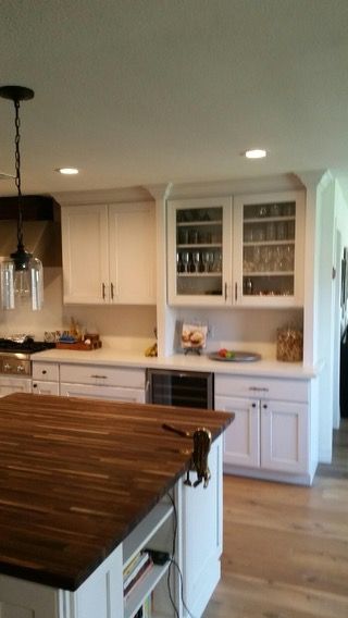 A kitchen with white cabinets and a large wooden island
