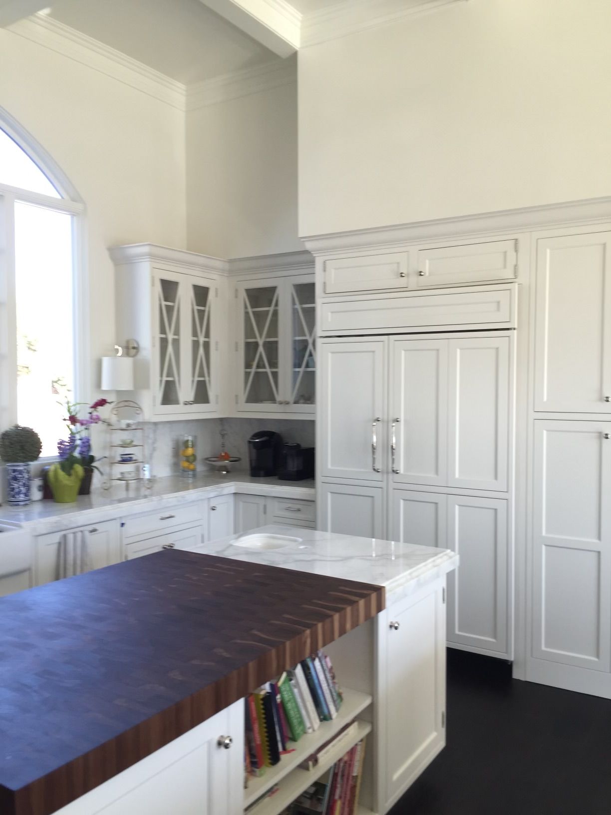 A kitchen with white cabinets and a large island with books on it