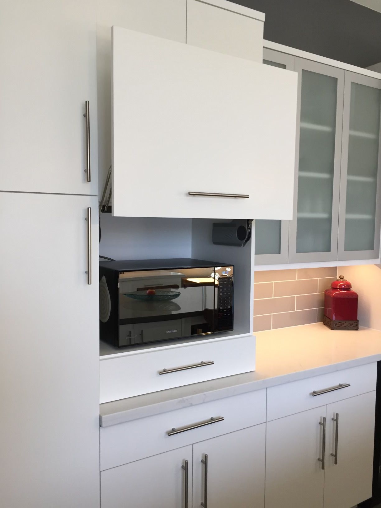 A kitchen with white cabinets and a microwave oven