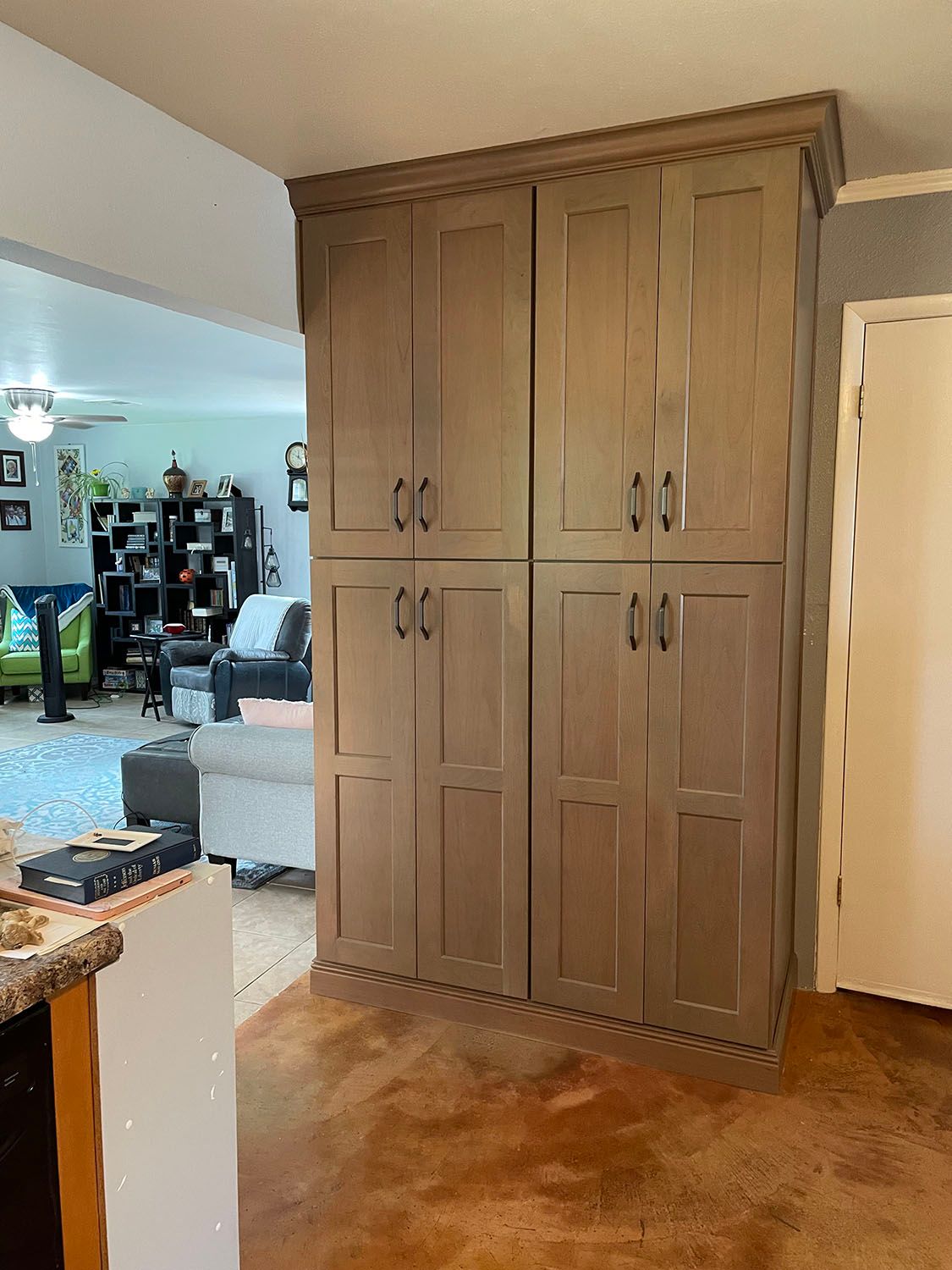 A room with a lot of cabinets and a living room in the background.