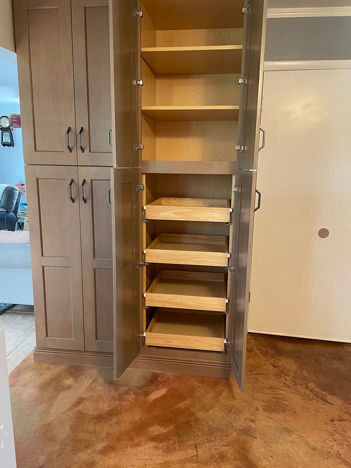 A pantry with drawers and shelves in a kitchen with the doors open.