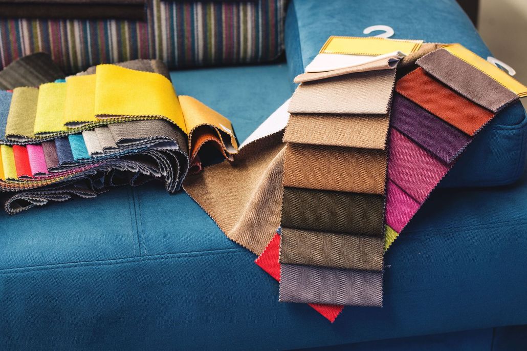 Fabric swatches in various colors and textures fanned out on a blue sofa.