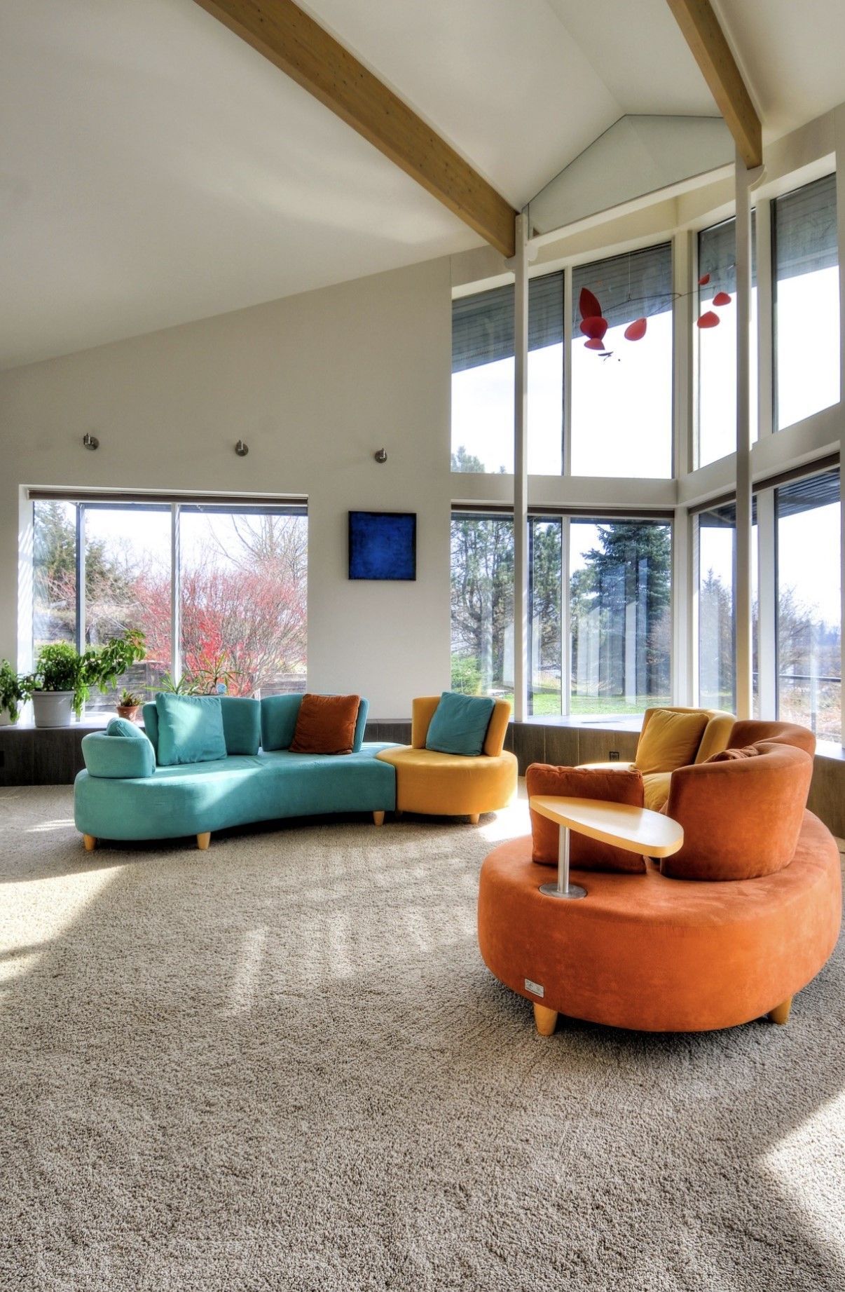 Bright living room with colorful curved sofas, tall windows, and a high vaulted ceiling