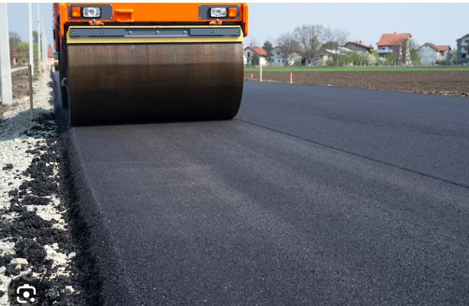 Road roller compacting fresh asphalt on a highway shoulder