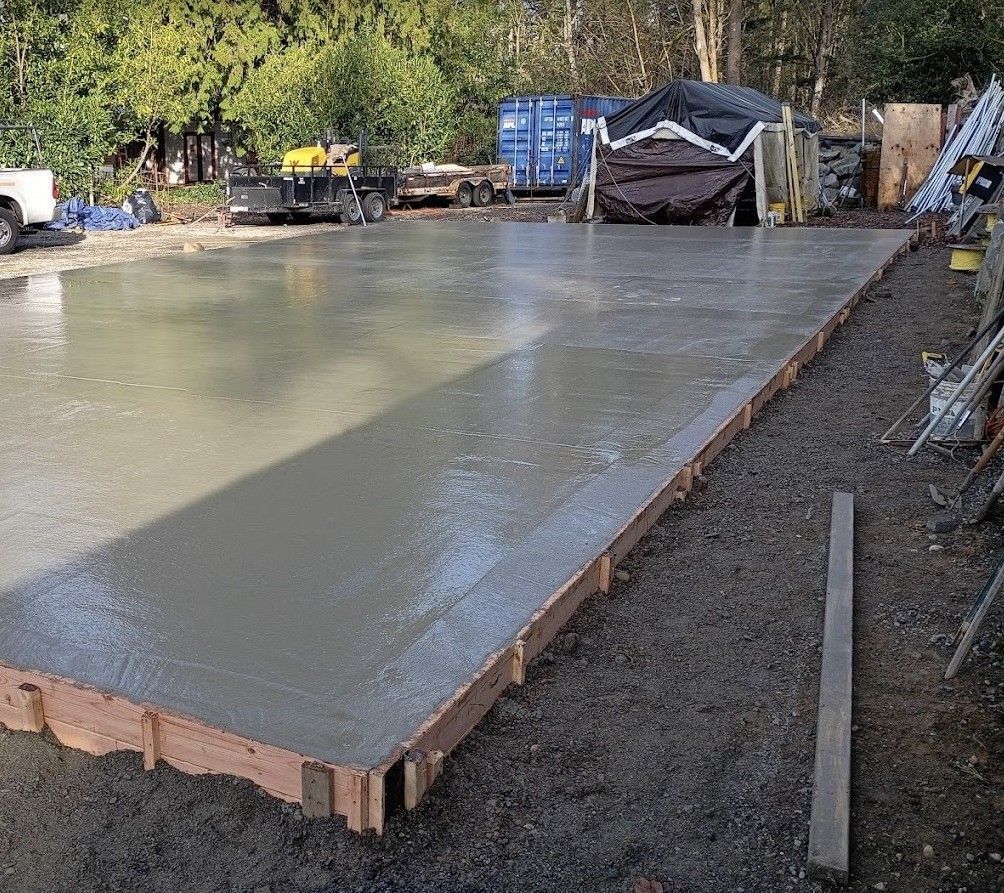 Fresh concrete slab foundation being poured at a wooded construction site