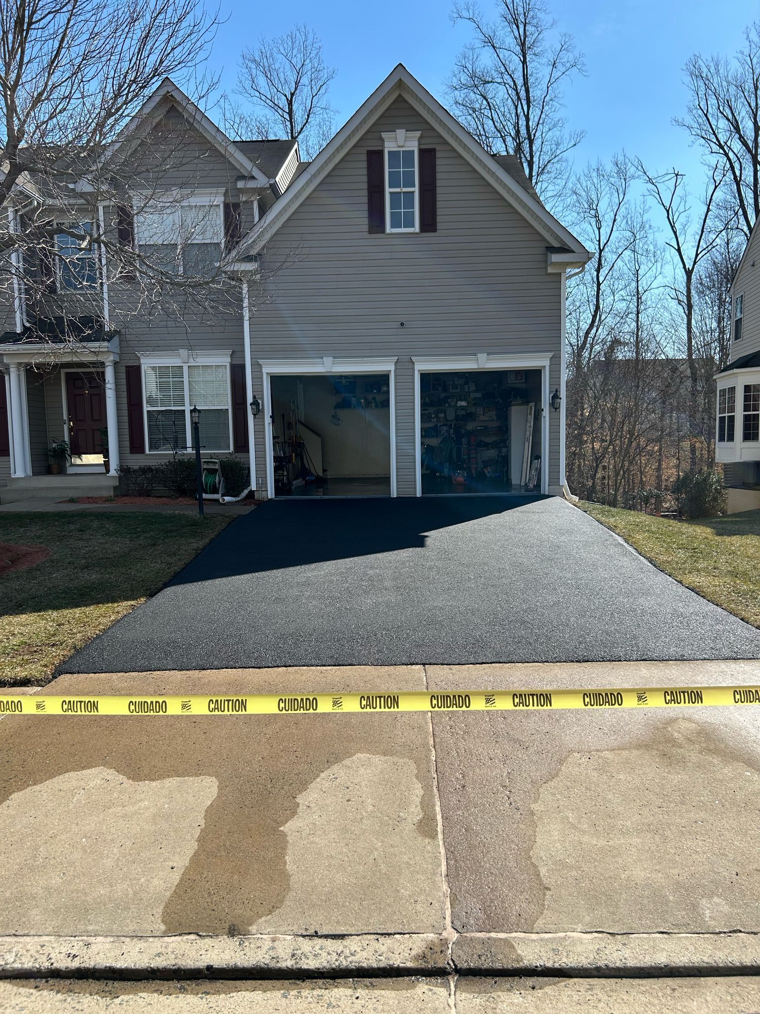Suburban house with driveway, open garage, and yellow caution tape across the curb.