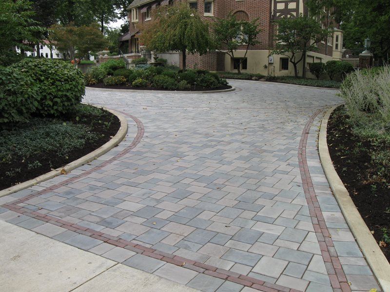 Curved brick walkway through landscaped garden beside a brick apartment building