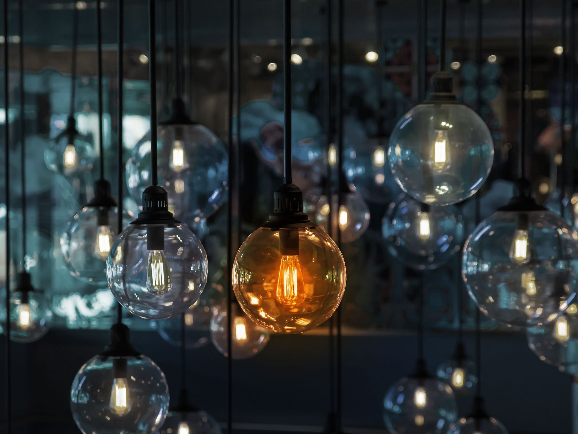 Clear glass globe lights hang from the ceiling, one glowing orange, the rest white.