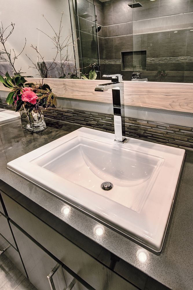 White rectangular sink in a bathroom with a chrome faucet. Dark gray countertop and cabinetry.